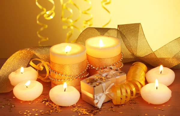 Belas velas, presentes e decoração em mesa de madeira no fundo amarelo — Fotografia de Stock