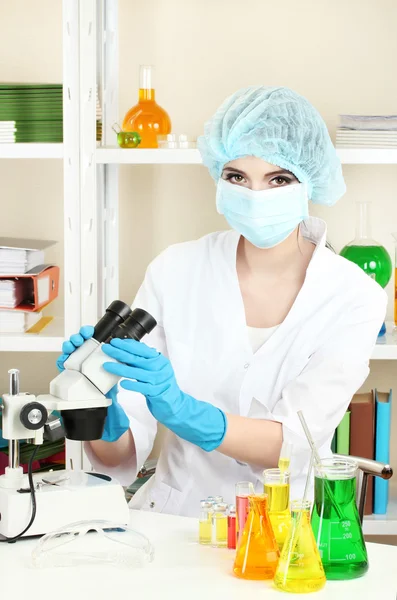 Jeune femme scientifique regardant le microscope en laboratoire de chimie — Photo