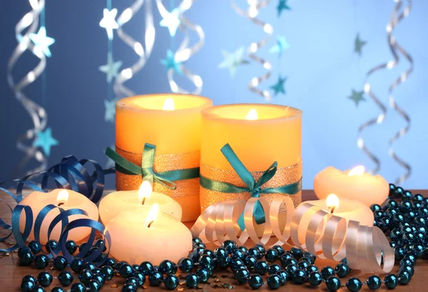 Beautiful candles, gifts and decor on wooden table on blue background Stock Image