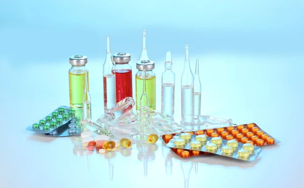 Tabletten und Ampullen auf blauem Hintergrund — Stockfoto