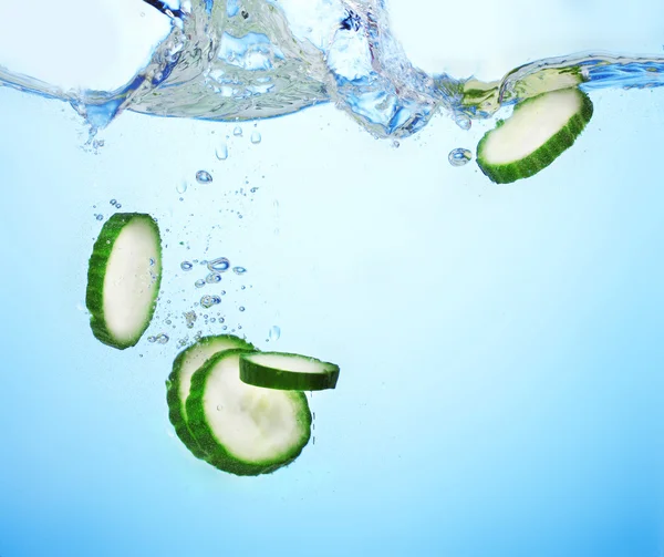 stock image Fresh sliced cucumber in water on blue background