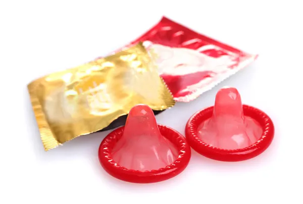 Красные презервативы с открытыми упаковками изолированы на белом — стоковое фото