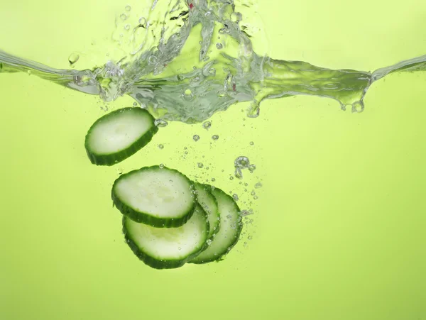 Pepino em fatias frescas em água sobre fundo verde — Fotografia de Stock