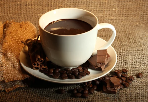 Чашка кофе, бобы и шоколад на фоне упаковки — стоковое фото