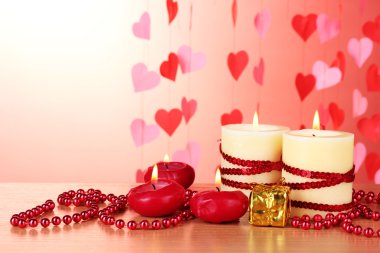 Beautiful candles with romantic decor on a wooden table on a red background clipart