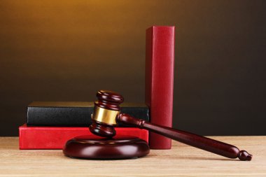 Judge's gavel and books on wooden table on brown background clipart