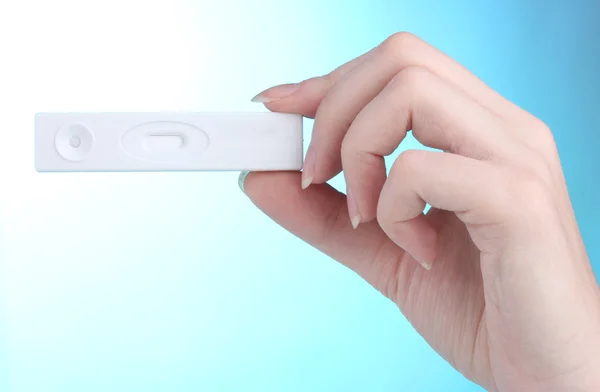 Pregnancy test in hand on blue background — Stock Photo, Image