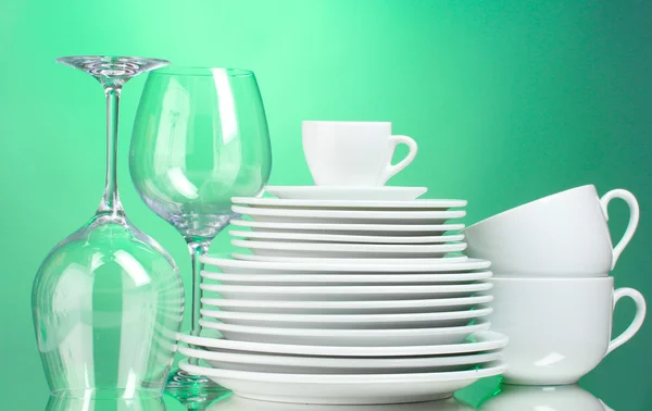 Piatti puliti, tazze e bicchieri su sfondo verde — Foto Stock