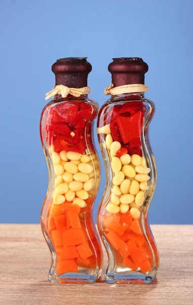 Zwei Flaschen mit rotem Pfeffer, Bohnen, Karotten für die Küche auf blauem Hintergrund — Stockfoto