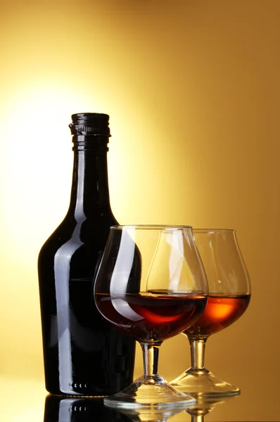 Brandy ve Sarı zemin üzerine şişe bardak — Stok fotoğraf