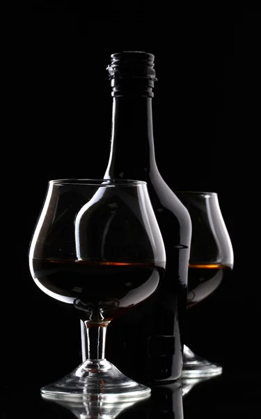Glasses of brandy and bottle on black background — Zdjęcie stockowe