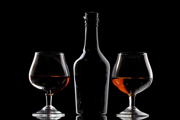 Gelas brendi dan botol pada latar belakang hitam — Stok Foto