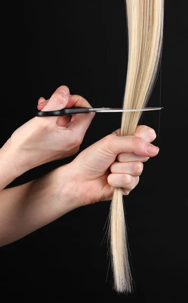 Shiny blont hår i frisör händer isolerade på svart — Stockfoto