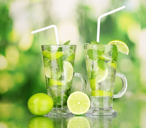 Vasos de cóctel con lima y menta sobre fondo verde —  Fotos de Stock