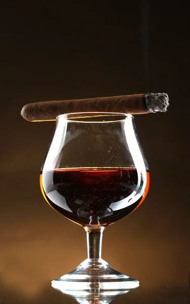 Vaso de brandy y cigarro sobre fondo marrón — Foto de Stock