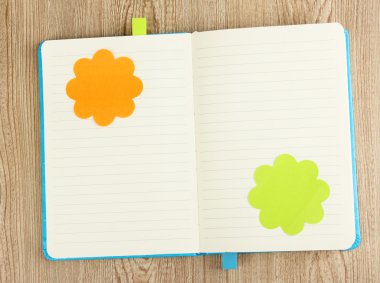 Open note book with stickies on wooden background clipart