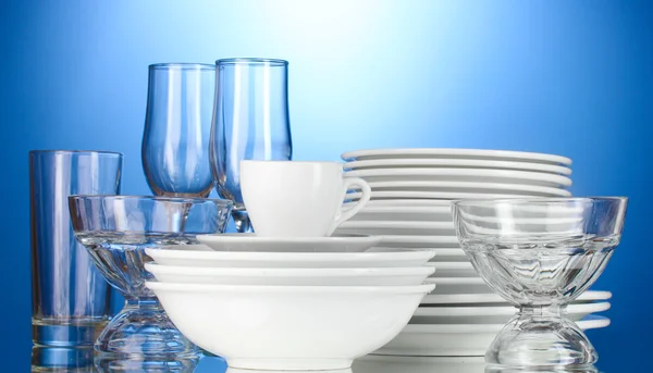 Άδειο μπολ, πιάτα, φλιτζάνια και ποτήρια σε μπλε φόντο — Φωτογραφία Αρχείου