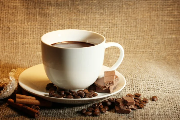 Tazza di caffè e fagioli, bastoncini di cannella e cioccolato sul fondo del sacco — Foto Stock