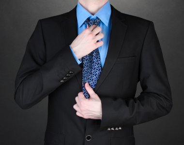 Businessman correcting a tie on black background clipart