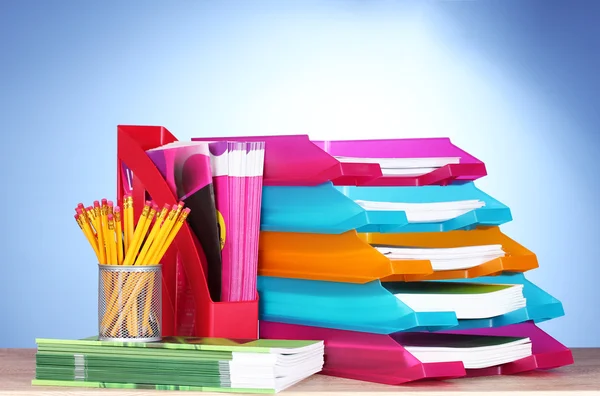 Helle Papiertabletts und Schreibwaren auf Holztisch auf blauem Hintergrund — Stockfoto