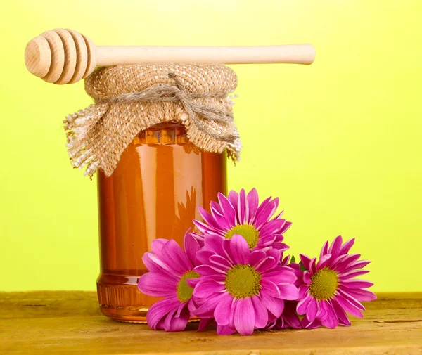 Γλυκό μέλι σε βάζο με drizzler στο ξύλινο τραπέζι σε πράσινο φόντο — Φωτογραφία Αρχείου