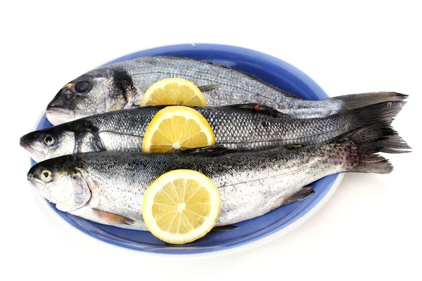 Pesci freschi con limone su piatto isolato su bianco — Foto Stock