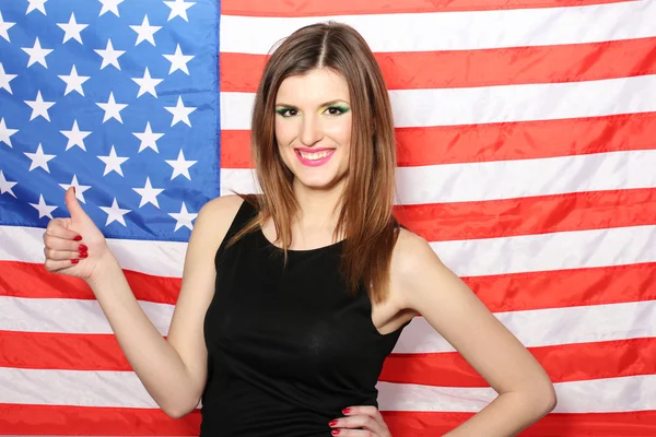 バック グラウンド上にアメリカ国旗を持つ美しい若い女性 — ストック写真