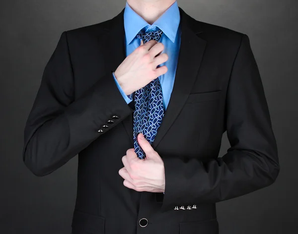 纠正在黑色背景上的一条领带的商人 — 图库照片