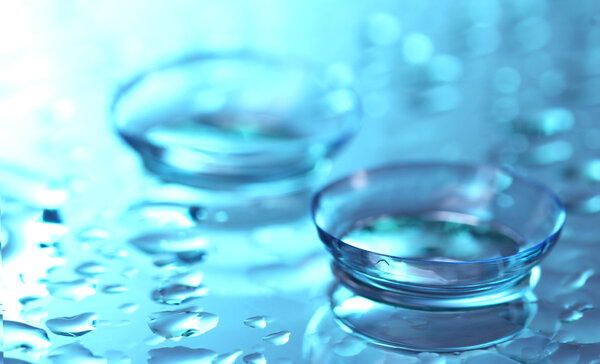 Contact lens with drops on blue background
