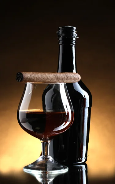 Palack és a pohár pálinkát és szivart a barna háttér — Stock Fotó