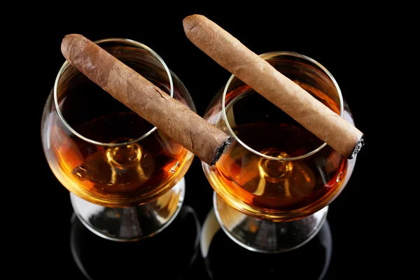 Due bicchieri di brandy e sigari su sfondo nero — Foto Stock