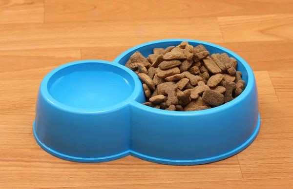 Dry dog food and water in blue bowl on the floor — Stock Photo, Image