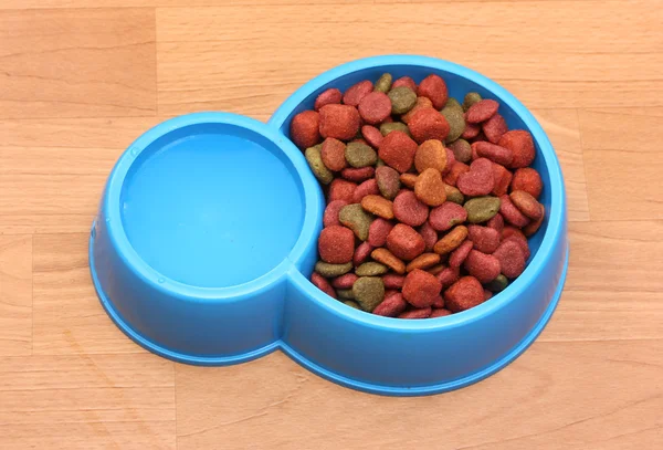Comida seca para perros y agua en tazón azul en el suelo — Foto de Stock