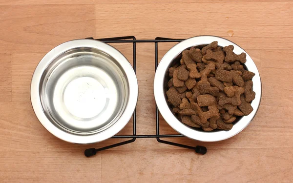 Сухой корм для собак и вода в металлических мисках на полу — стоковое фото