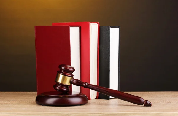 Soudcova kladívka a knihy o dřevěný stůl na hnědé pozadí — Stock fotografie