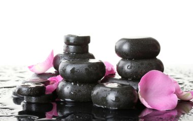 Spa stones with drops and rose petals on white background