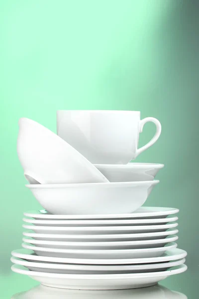Platos limpios y taza sobre fondo verde — Foto de Stock