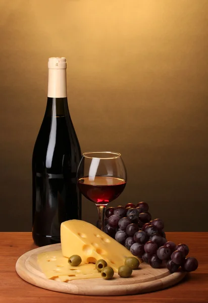 Botella de gran vino con vino y queso sobre mesa de madera sobre fondo marrón — Foto de Stock
