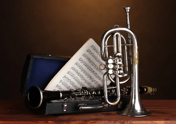 Tromba antica e clarinetto in caso su tavolo di legno su sfondo marrone — Foto Stock