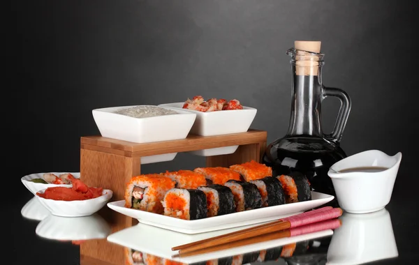 Delicious sushi on plate, chopsticks, soy sauce, fish and shrimps on gray background — Stock Photo, Image