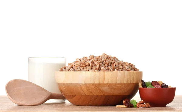 Boiled buckwheat in a wooden bowl with a glass of milk on wooden table isolated on white — Stock Photo, Image