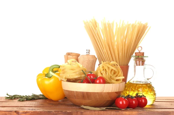 Spaghettis, nouilles dans un bol, bocal d'huile et légumes sur table en bois isolé sur blanc — Photo