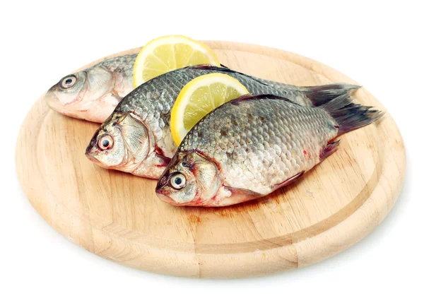 Свежие рыбы с лимоном на деревянной доске, изолированные на белом — стоковое фото