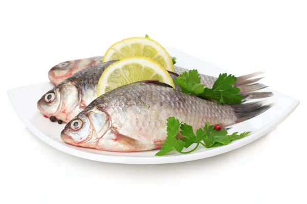 Färska fiskar med citron och persilja på plattan isolerad på vit — Stockfoto