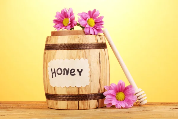 Süßer Honig im Fass mit Nieselregen auf Holztisch auf gelbem Hintergrund — Stockfoto