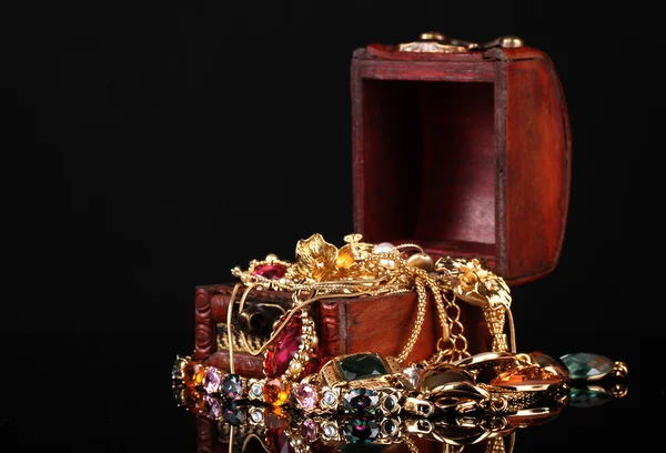 Dřevěná truhla plná zlatých šperků na černém pozadí — Stock fotografie