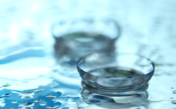 Contact lens with drops on blue background