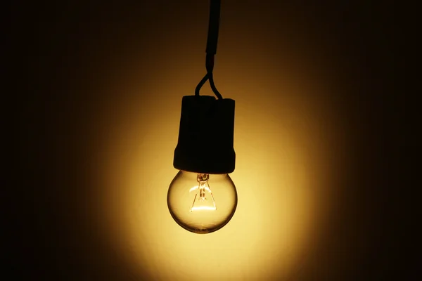 Eine beleuchtete Glühbirne auf gelbem Hintergrund — Stockfoto