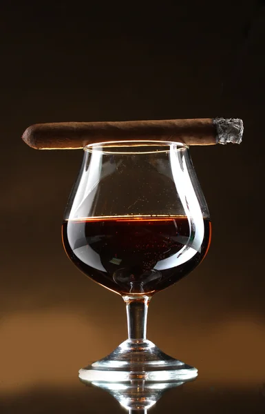 Verre de brandy et cigare sur fond brun — Photo