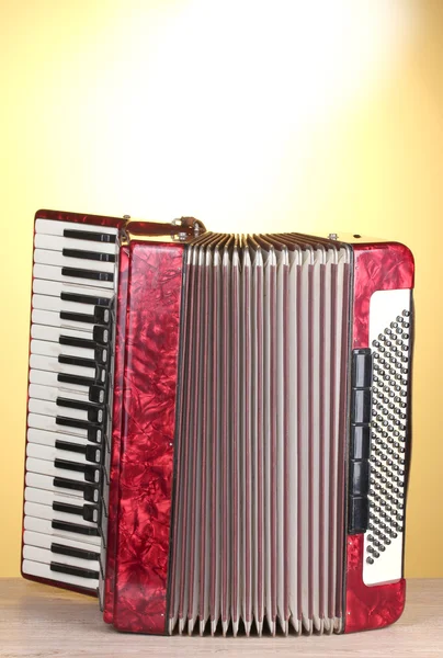 stock image Retro accordion on wooden table on yellow background